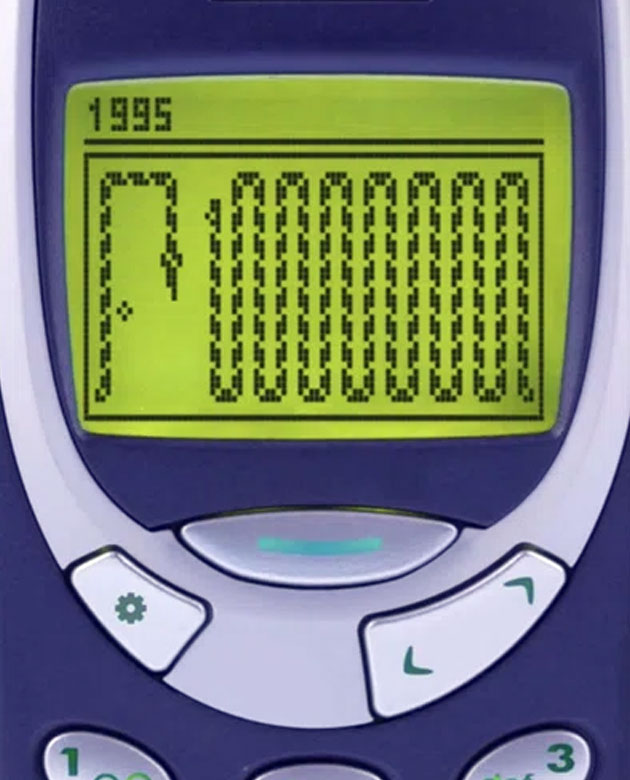 Classic Nokia 3310 displaying Snake game on monochrome green screen, dark studio background